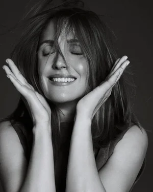 Rose Byrne smiling with eyes closed and hands framing her face in a black and white portrait for Marie Claire Australia.