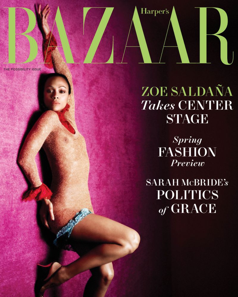 Zoe Saldana graces Harper's Bazaar cover in a glittery gold outfit and red accessories, posing against a vibrant pink backdrop with magazine text.