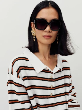 Model wearing dark sunglasses and striped polo shirt against white background for Chanel Cruise collection