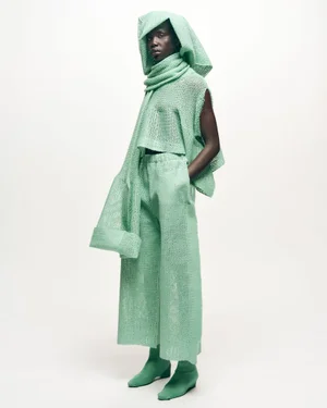Model Naomi Apajok in a mint green textured knit hooded top and matching wide trousers against a white seamless background.