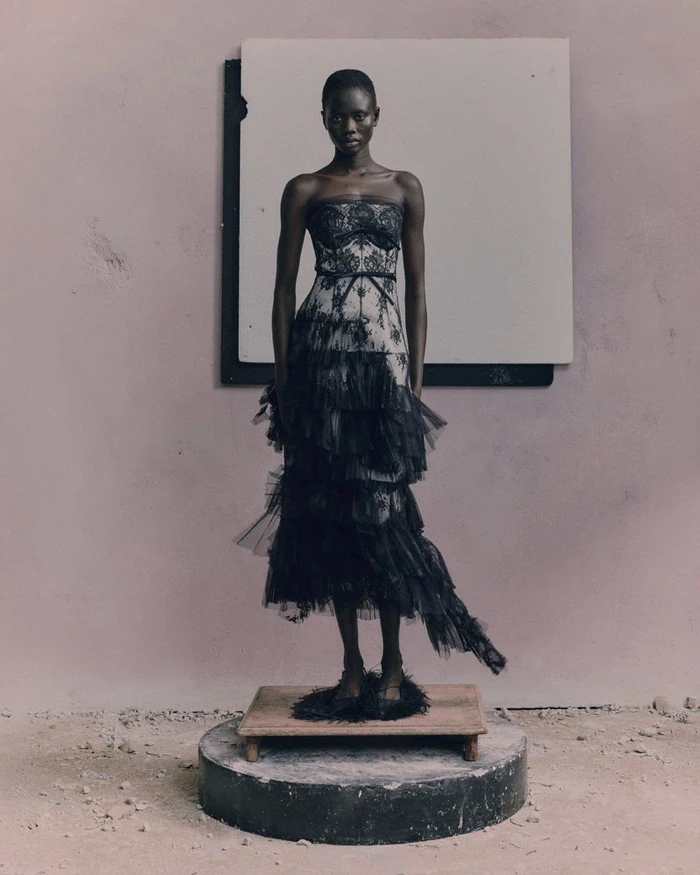 Model Chol Khan standing on a pedestal in a strapless tiered black lace and tulle gown for the Erdem Pre-Fall 2026 lookbook.