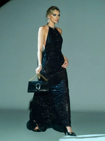Elegant woman in a black sequin gown poses with a black handbag. Fashionable and stylish, showcasing an evening-wear look.