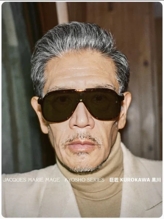 Portrait of an East Asian man with grey hair wearing dark aviator sunglasses and a beige turtleneck.