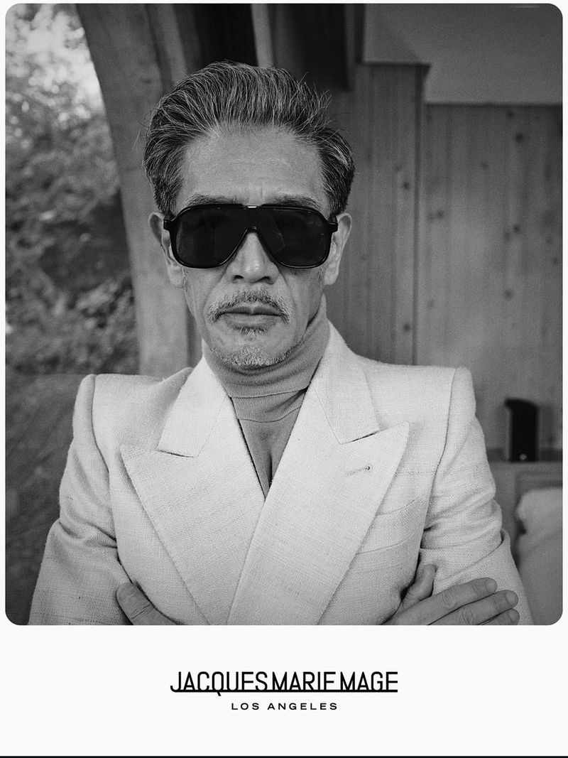 Monochrome portrait of an East Asian man wearing large black sunglasses and a light-toned structured suit jacket.