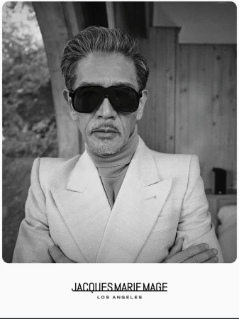 Monochrome portrait of an East Asian man wearing large black sunglasses and a light-toned structured suit jacket.
