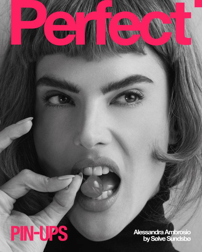 Close-up studio shot of Alessandra Ambrosio on a magazine cover, holding a cherry near her mouth, with bold text and graphic design elements.