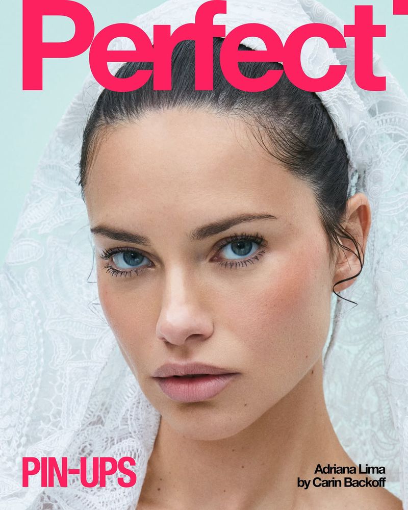 Close-up magazine cover featuring model Adriana Lima in a lace veil with bright, clear lighting on a light blue background.