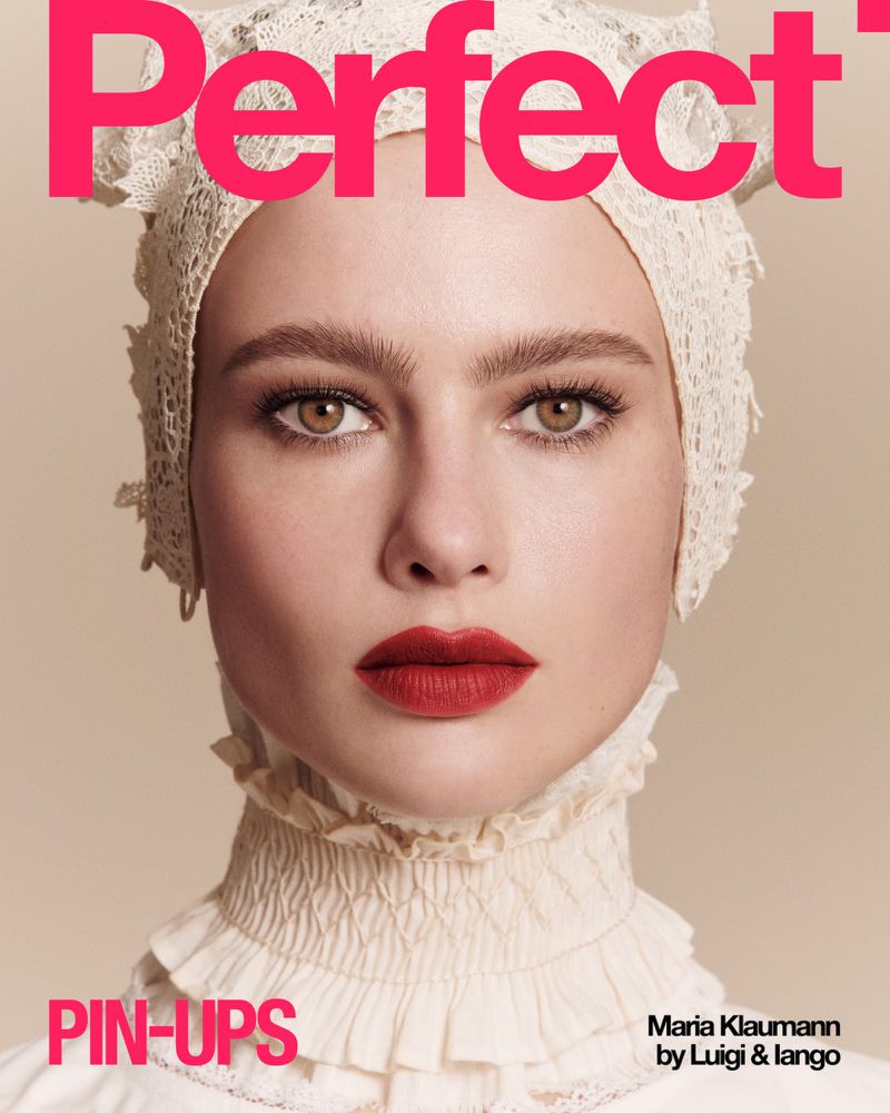 Close-up portrait of a fair-skinned woman wearing a vintage-style lace bonnet and collar, posing for a magazine cover, studio shot.