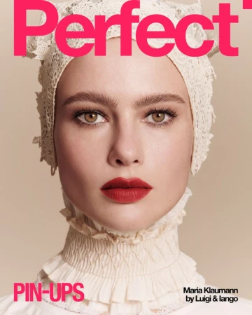 Close-up portrait of a fair-skinned woman wearing a vintage-style lace bonnet and collar, posing for a magazine cover, studio shot.