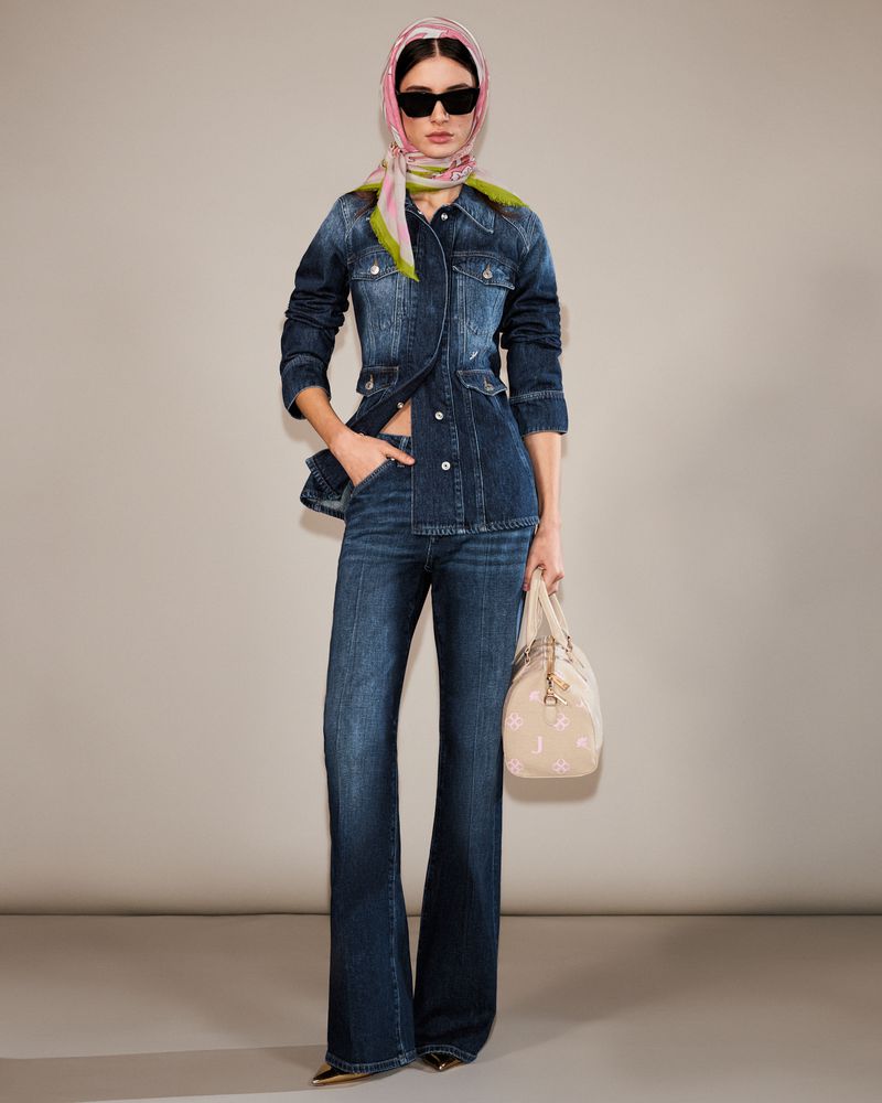 Full shot of a fashion model in a blue denim outfit, accessorized with a headscarf and handbag, striking a pose against a neutral backdrop.