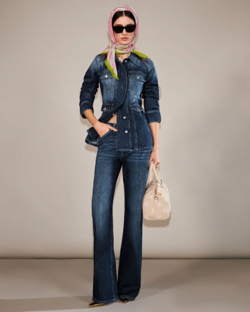 Full shot of a fashion model in a blue denim outfit, accessorized with a headscarf and handbag, striking a pose against a neutral backdrop.