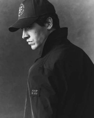 Monochrome profile portrait of model Marco Bellotti wearing a black JOOP! Jeans jacket and baseball cap.