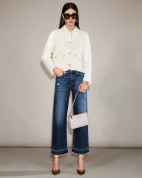 Model Alice Ferazzoli poses in a cream quilted jacket, dark wash wide-leg jeans, sunglasses, and heels against a grey studio backdrop.