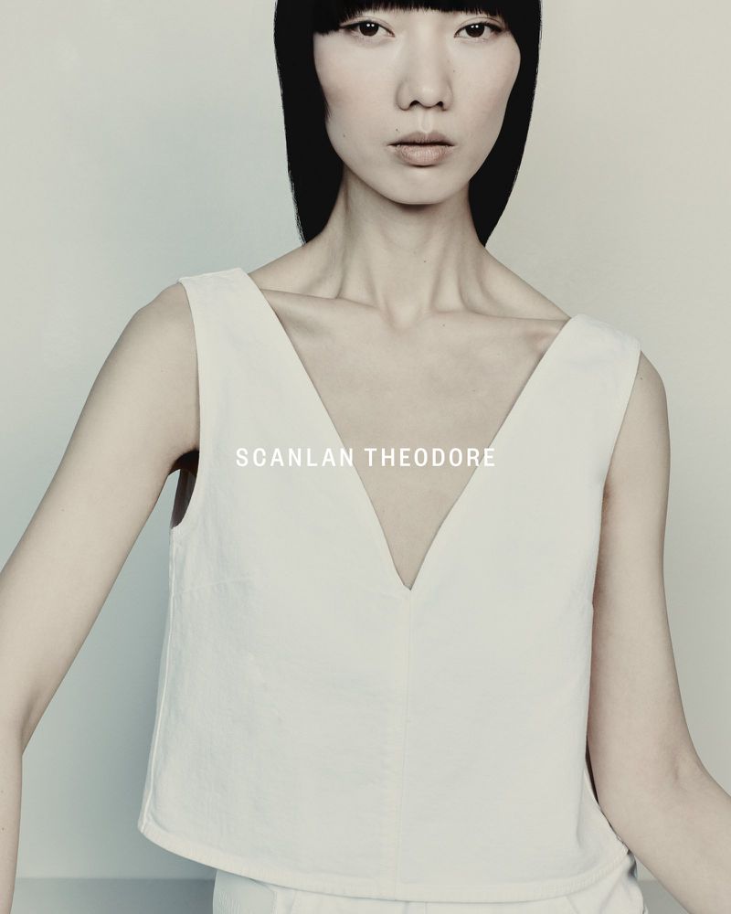 Headshot of a light-skinned model with a blunt black bob and sleeveless white top against a white background. Fashion editorial style.