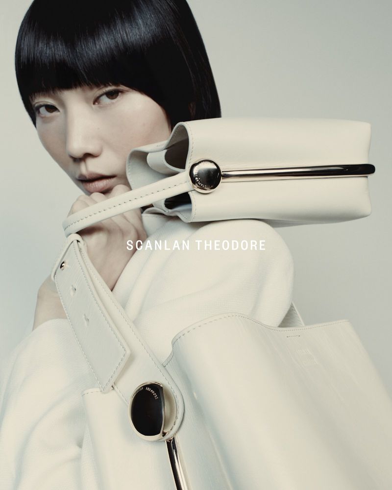 Fashion shot featuring an Asian woman model showcasing a white handbag and purse from Scanlan Theodore, set against a soft, neutral background.