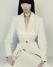Model Yixin Zhao wearing a tailored cream belted blazer and holding a structured handbag for Scanlan Theodore.