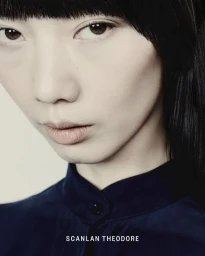 Close-up portrait of model Yixin Zhao with straight black bangs wearing a dark navy buttoned shirt for Scanlan Theodore.