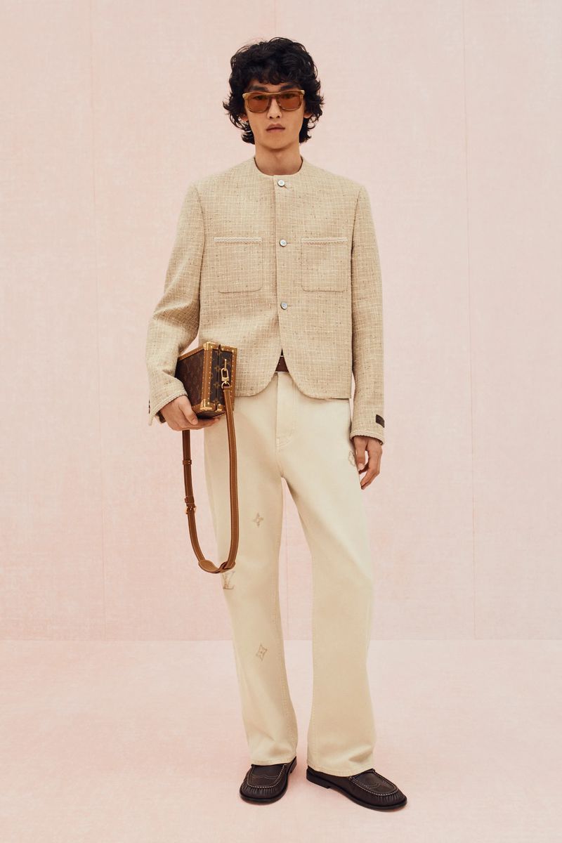 Model Bai wearing a beige collarless tweed jacket, cream trousers, and sunglasses against a pale pink backdrop for Louis Vuitton.