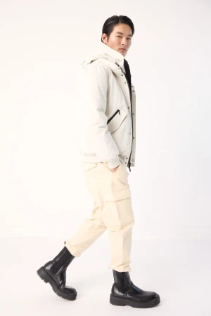 A stylish Asian man walking in a hooded jacket, cargo pants, and platform boots against a clean white background, fashion forward.