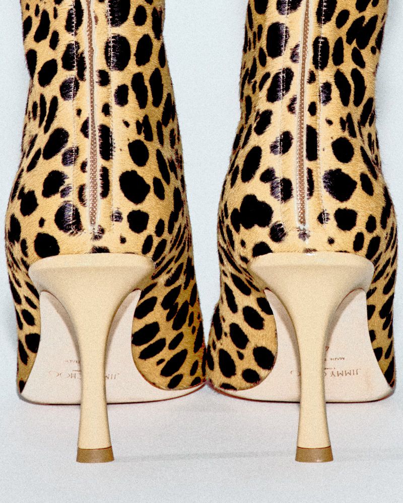 Leopard print ankle boots with stiletto heels, showcasing the back view of the designer footwear in a studio setting.