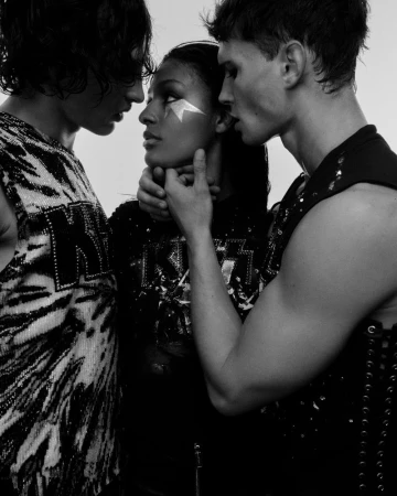 Three fashion models pose in black-and-white studio shot wearing 'Kiss' branded clothing, and one with face paint and a dramatic pose.