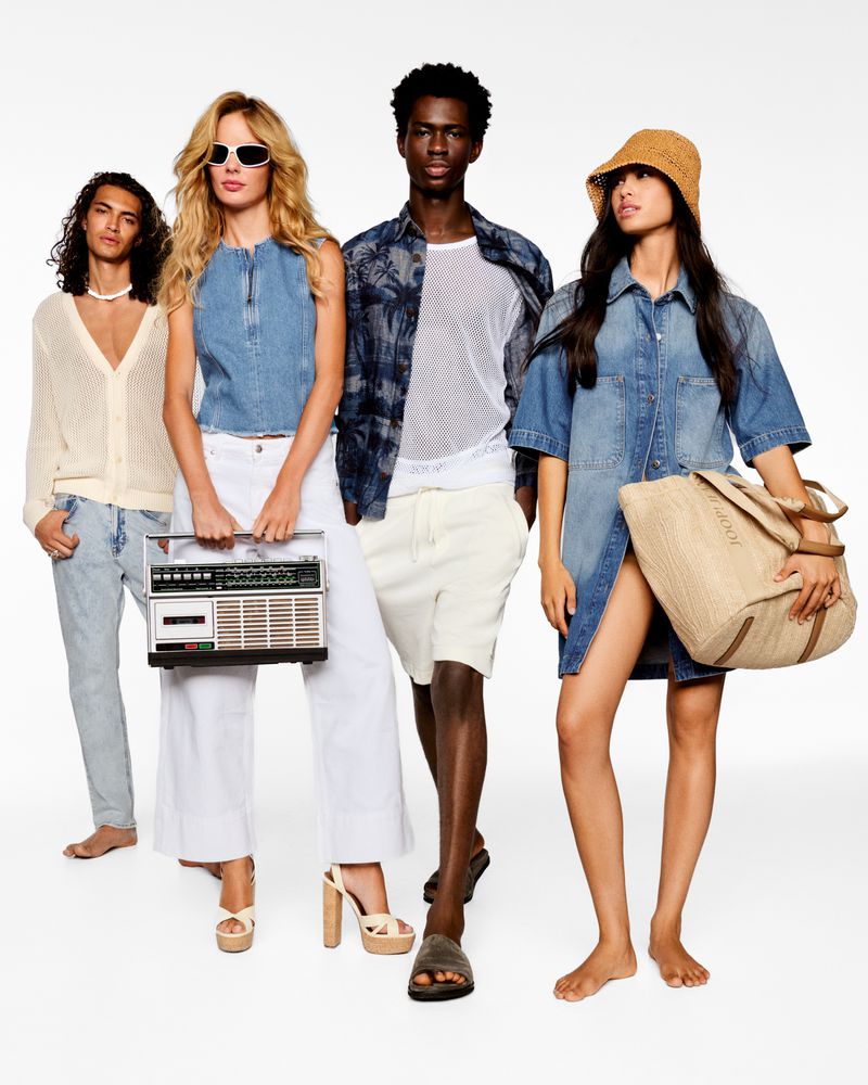 Group of four fashion models in casual summer clothing pose in a studio with a vintage boombox and tote bag.