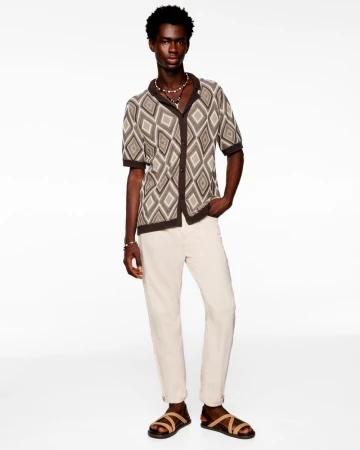 Model wearing patterned short-sleeve shirt and light trousers against white seamless background for JOOP Lookbook Spring/Summer 2026
