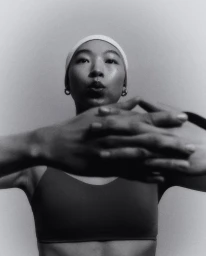 Model Maureen Tang stretching with hands clasped in front of her face wearing activewear for lululemon