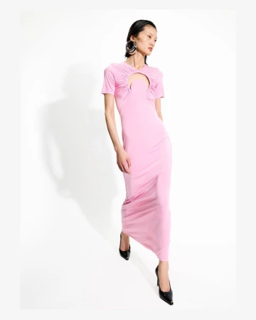Model in a pink cutout midi dress with large round earrings against a plain white background