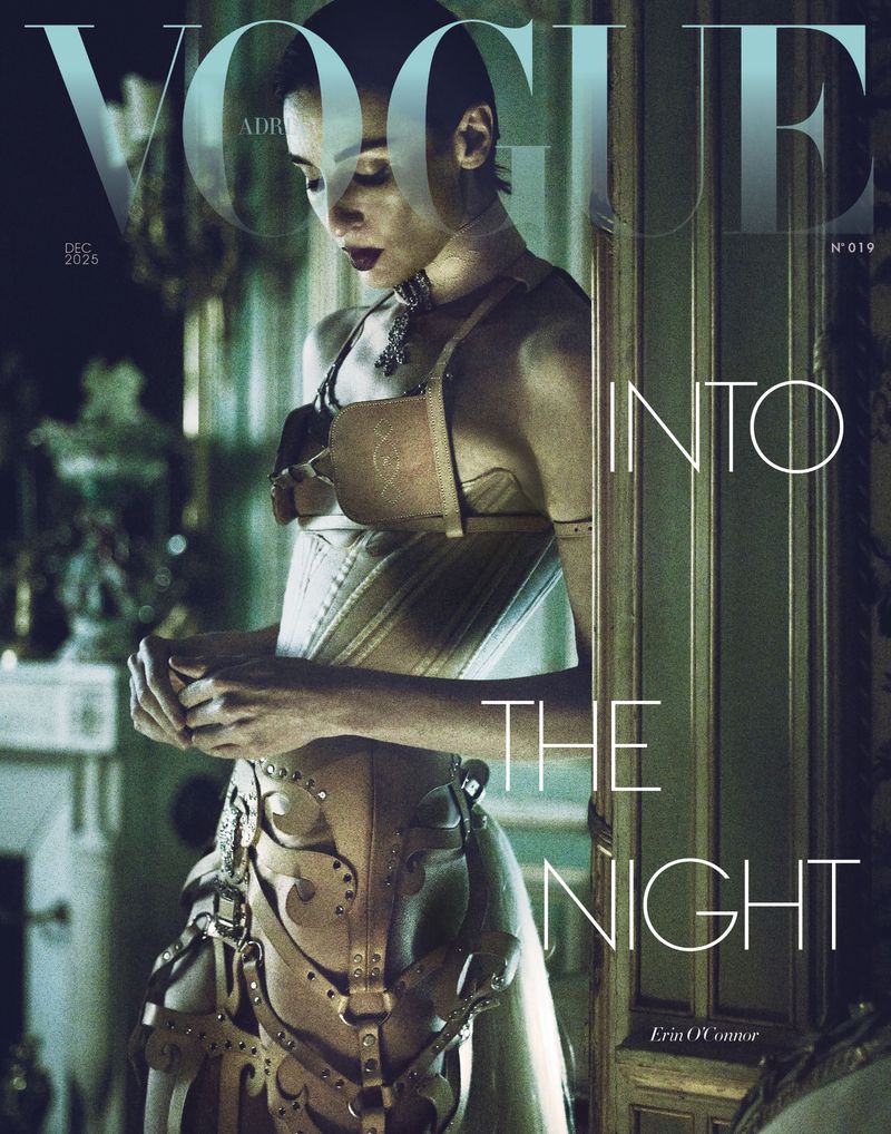 Vogue magazine cover featuring a woman in a structured, light brown garment, captured in a dimly lit, elegant interior setting.