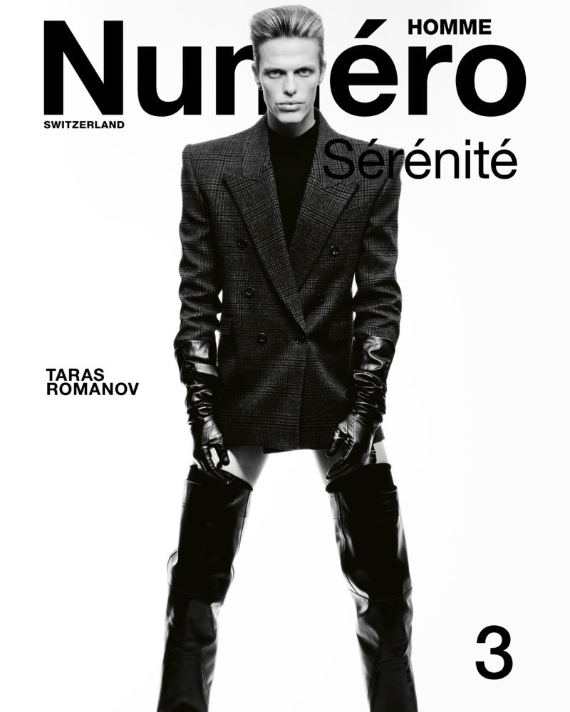 Numero Homme magazine cover featuring a male model in a grey suit, gloves, and thigh-high boots, on a white background.