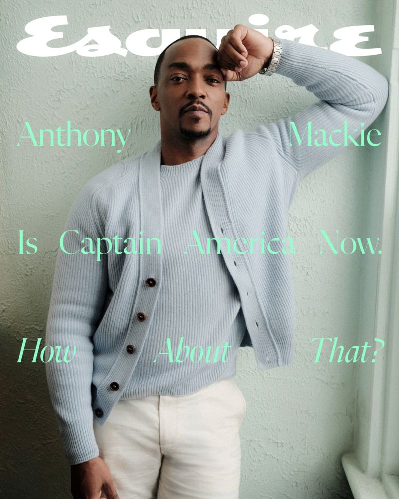 Magazine cover featuring Anthony Mackie in a light blue cardigan and white pants, posing in front of a textured wall with teal text.