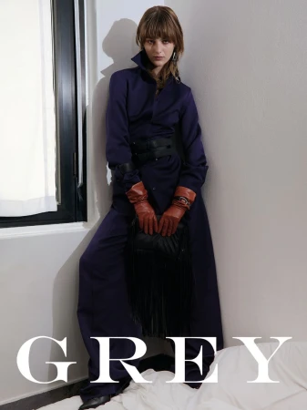 Model Matilda Navratil in a dark navy jumpsuit and brown leather gloves posing in a corner for Grey Magazine Italy.