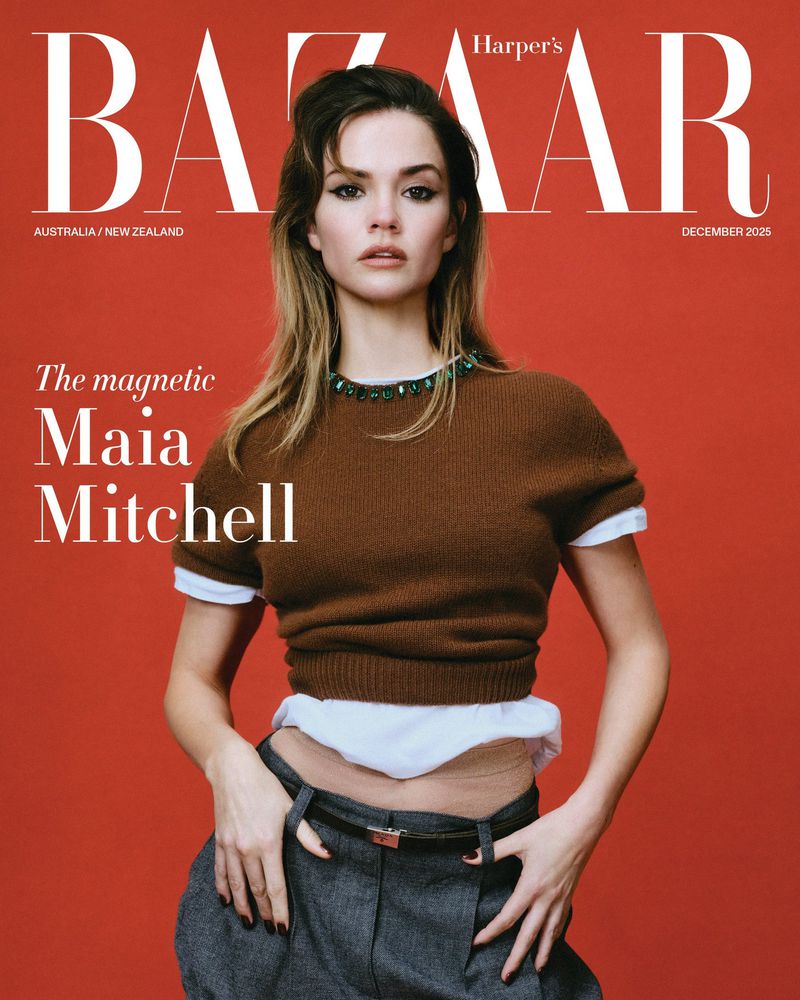 Magazine cover featuring Maia Mitchell wearing a brown sweater, grey pants, and posing against a red backdrop with magazine text.