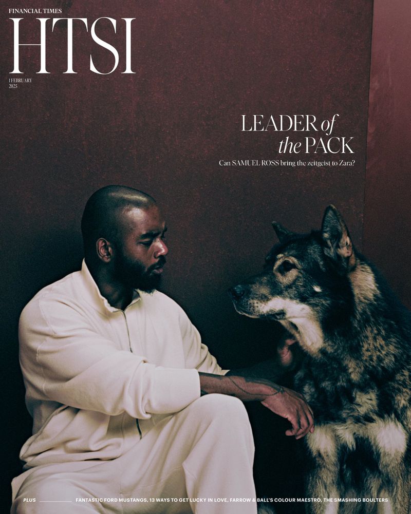 Magazine cover featuring a black man in a white tracksuit sitting next to a large dog against a dark brown background.