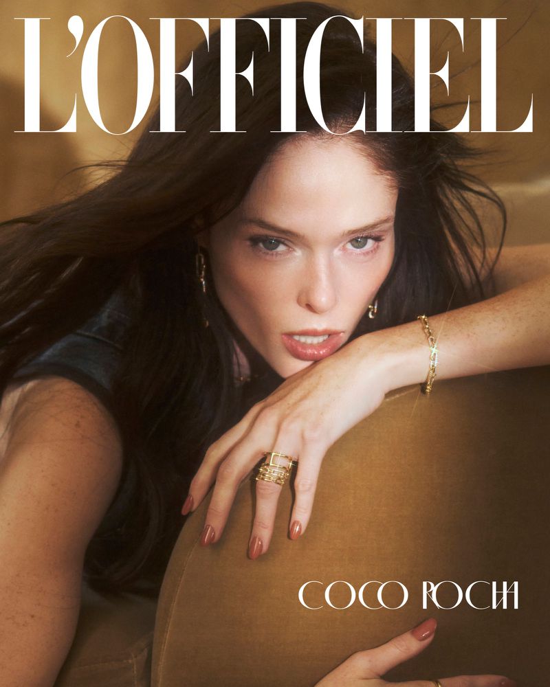 L'Officiel magazine cover featuring a brunette woman wearing jewelry, posing against a tan backdrop with neutral, soft lighting.