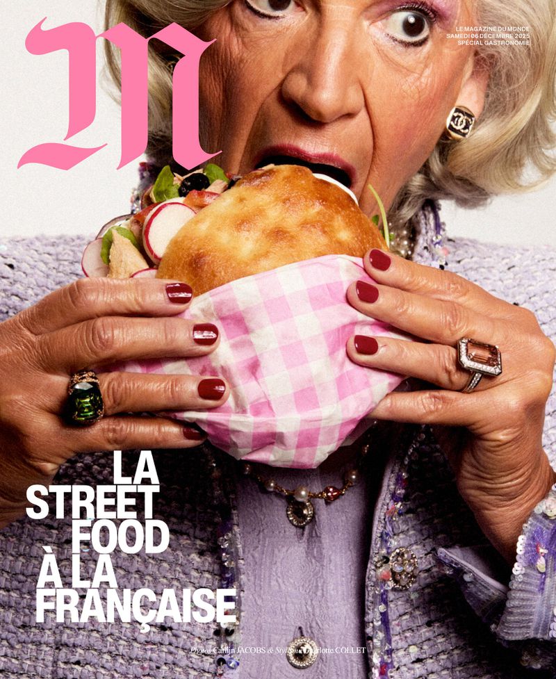 Magazine cover featuring an elderly woman in a lilac outfit eating a large sandwich, adorned with jewelry and a Chanel earring.