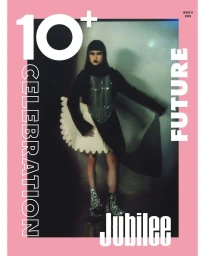 Model in black clothing with white pleated skirt and sparkly boots standing against a plain backdrop with bold typography framing the image.