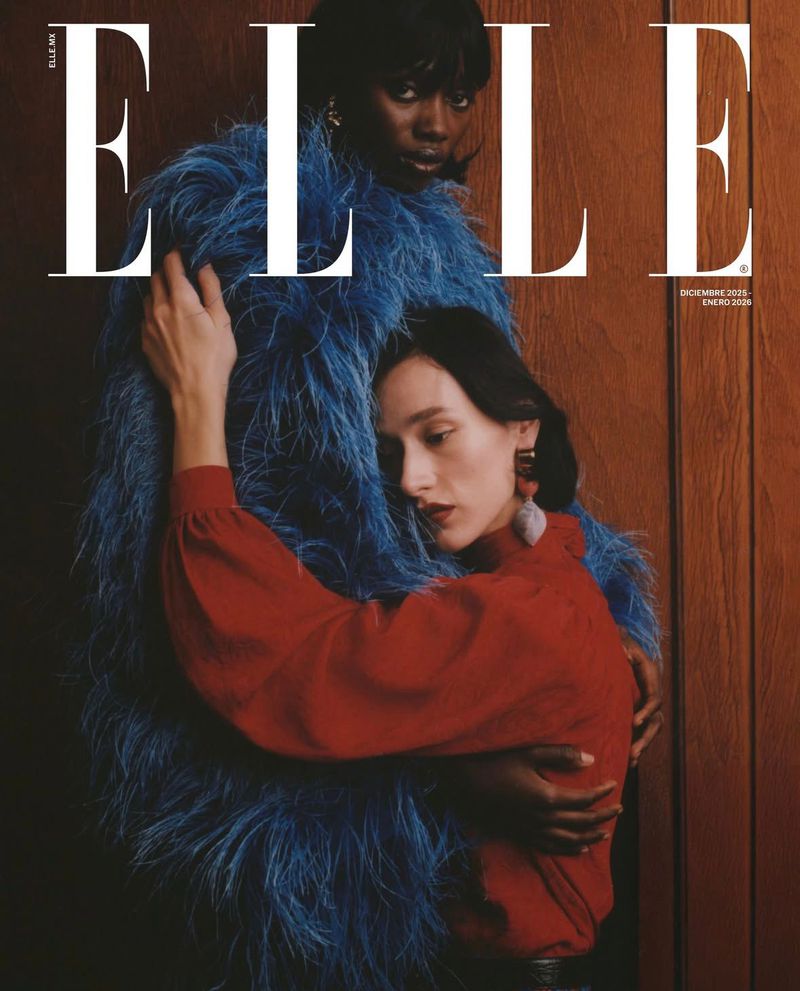 Two women are posing on a cover of Elle magazine, one in a red dress and the other in a blue feathered coat against a brown backdrop.