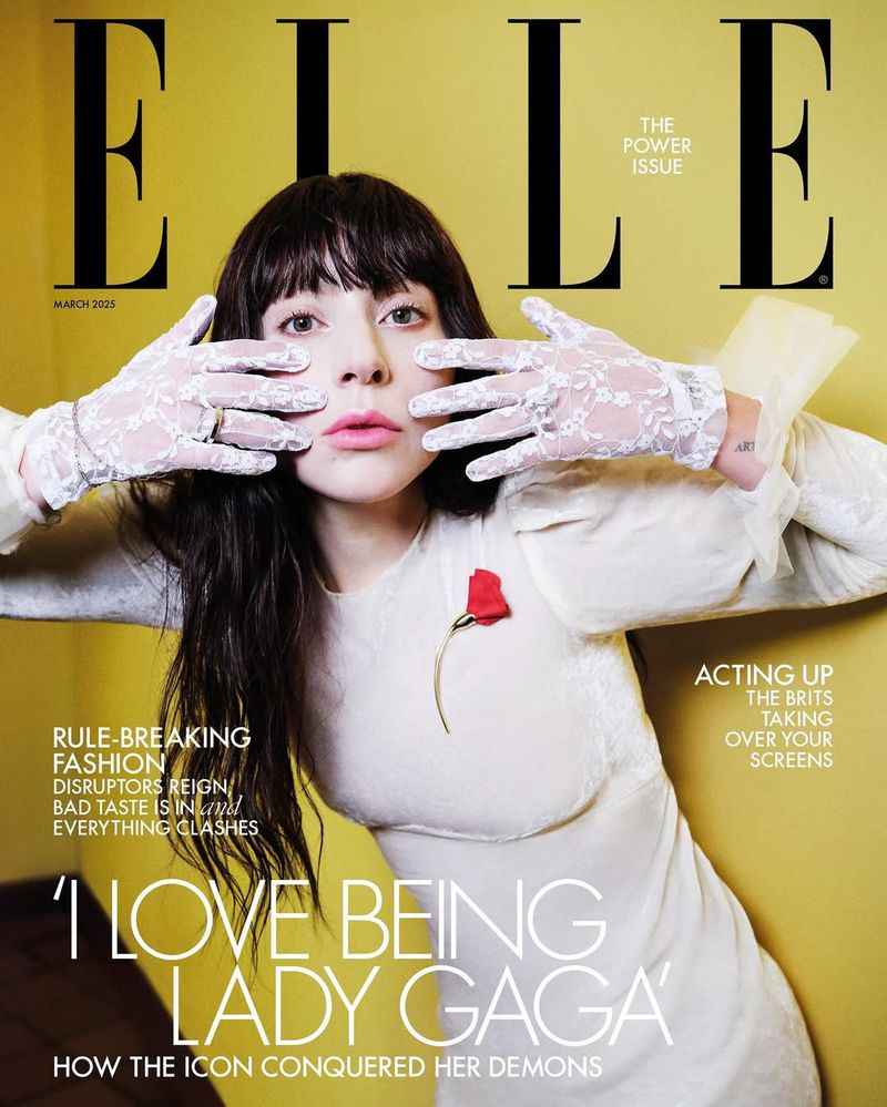 Magazine cover featuring a woman with black hair and bangs, wearing a white dress and lace gloves, posing against a yellow background.