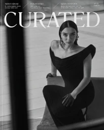 Merve Dizdar wearing an off-the-shoulder black gown seated for the Curated Magazine Fall 2025 cover.