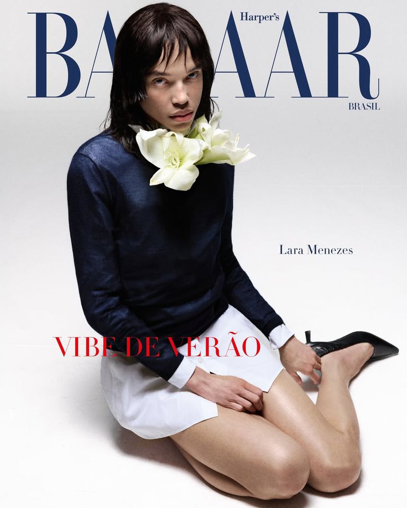 Lara Menezes poses on a white background, adorned with white flowers, captured in a fashion editorial style cover shot.