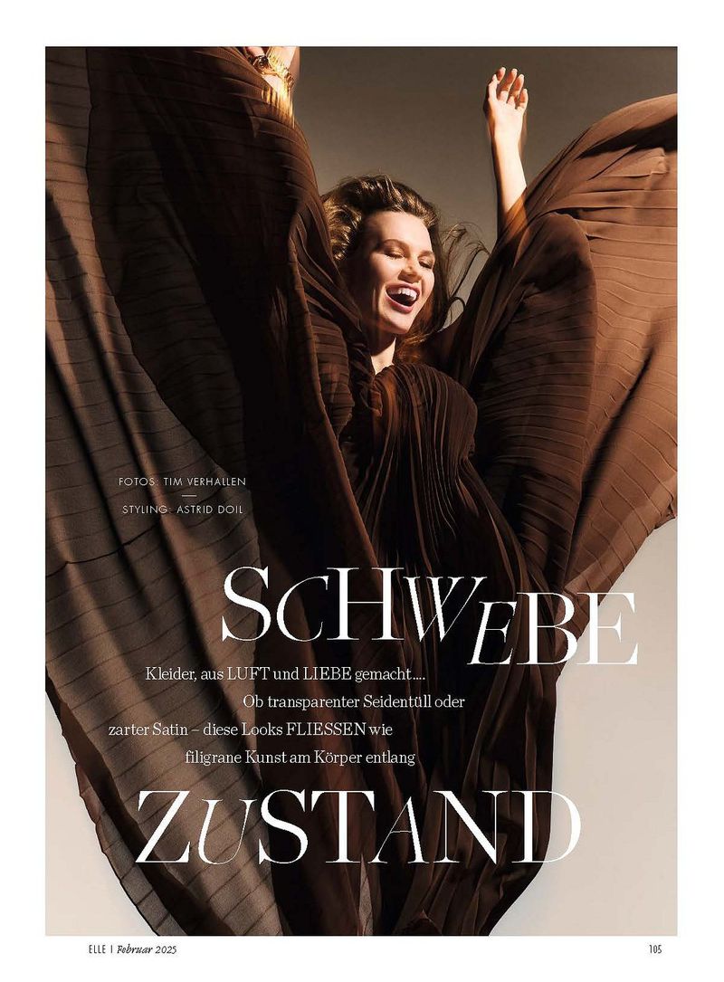 Model in a brown pleated dress with arms raised against a neutral studio background for Elle Germany February 2025