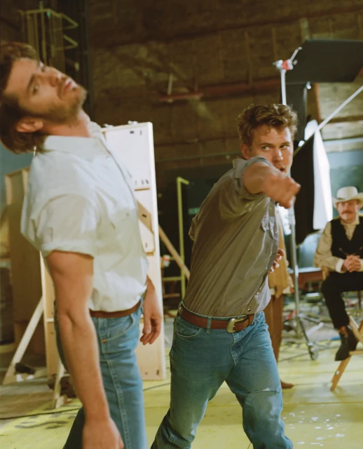 Two men in a physical altercation in what appears to be a production studio setting with another man sitting in the background.