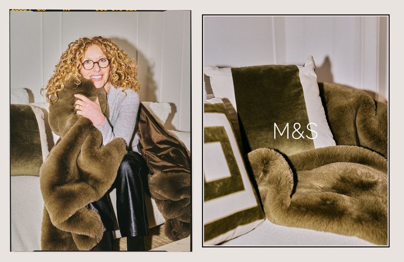Indoor shot of an adult female with curly hair, glasses, grey shirt and black pants, sitting on a white couch holding a brown blanket.