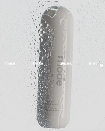 Close-up studio shot of a white Rhode skincare bottle covered in water droplets against a white background with visible brand text.