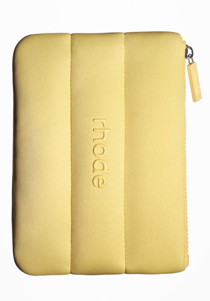 A light yellow, padded sleeve with vertical embossed lines and a zipper closure, displayed against a clean, white background.