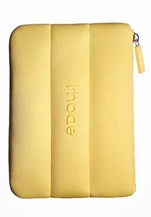 Yellow padded cosmetic pouch with debossed rhode branding and top zipper against a solid white background.