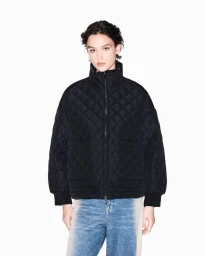 Model wearing a black quilted jacket and blue jeans against a bright white studio background for Armani Exchange F/W 2025.