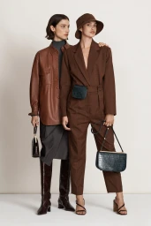 Two female models posing in brown autumn fashion apparel and leather handbags against a plain white studio backdrop.